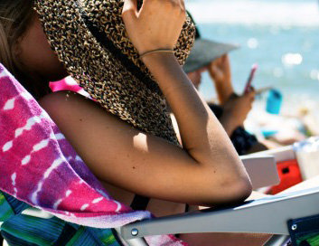Kvinna som solar i en solstol och håller en hatt över ansiktet.